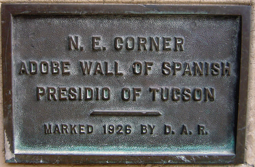 An historical plaque; clear wording reads “N. E. Corner Adobe Wall of Spanish Presidio of Tucson / Marked 1926 by D.A.R.”