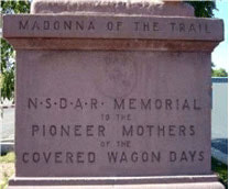 Statue base, front, reads, “NSDAR Memorial to the Pioneer Mothers of the Covered Wagon Days.”