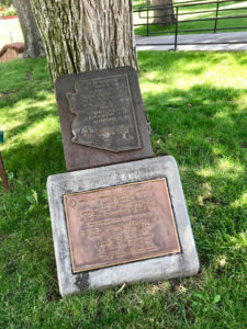 A snapshot of the original marker with the Arizona-shaped marker above, against the base of a tree. Marker text is in the body of this page.