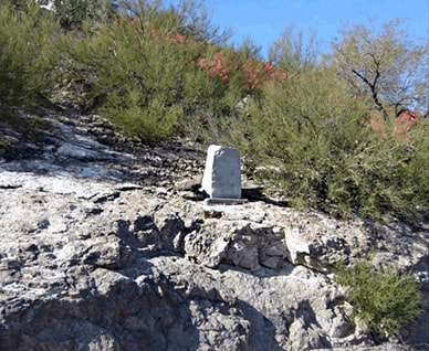 A snapshot of an upright stone marker on a rocky promontory in the mid-ground, Sentinel Peak, Tucson.