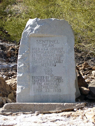 An historical marker cut into a standing stone reads: “Sentinel Peak / Used as a lookout and for signal fires by the Indians prior to and since 1692 and later by early settlers / Erected by Tucson Chapter, Daughters of the American Revolution, Feb 22, 1933”