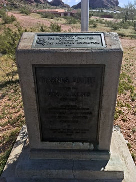 A snapshot of a standing marker with a small plaque on top and a larger plaque on the front. Text is unreadable.