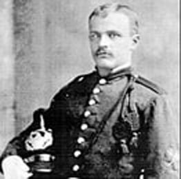 A studio photographic portrait of Will Croft Barnes in uniform, holding his hat.