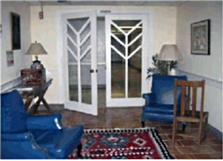 A snapshot of a room interior with doors, two blue chairs, and tables with lamps.