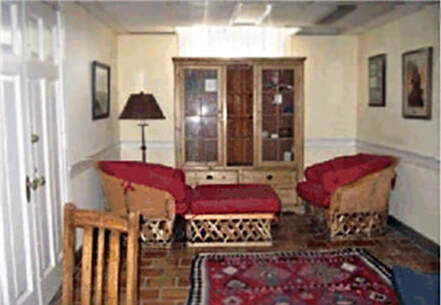 A snapshot of the same interior taken from the other side with two Southwest style chairs, an ottoman, and a cabinet.