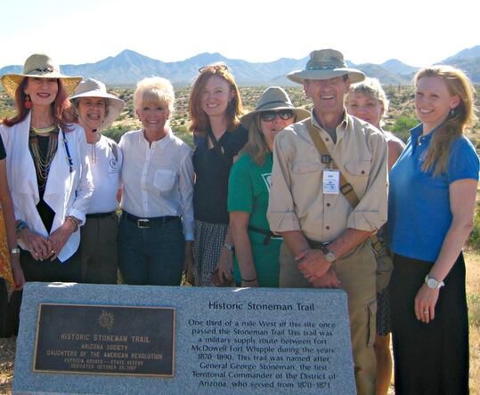 A snapshot of a group of adults behind the larger marker. The original plaque is on the left side of the marker with additional words etched onto the right side. Marker text is in the body of this page.