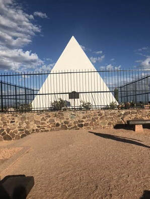 A snapshot of a white pyramid in a fenced area, the tomb of Gov George W P Hunt.