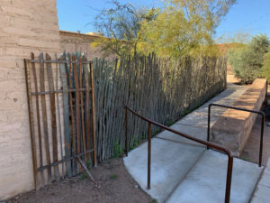 A snapshot of a sidewall along an adobe wall, separated by a fence.