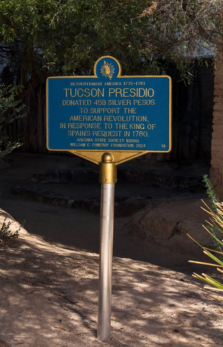 A photo showing the four foot blue marker on a post in front of the Tucson Presidio's east wall.